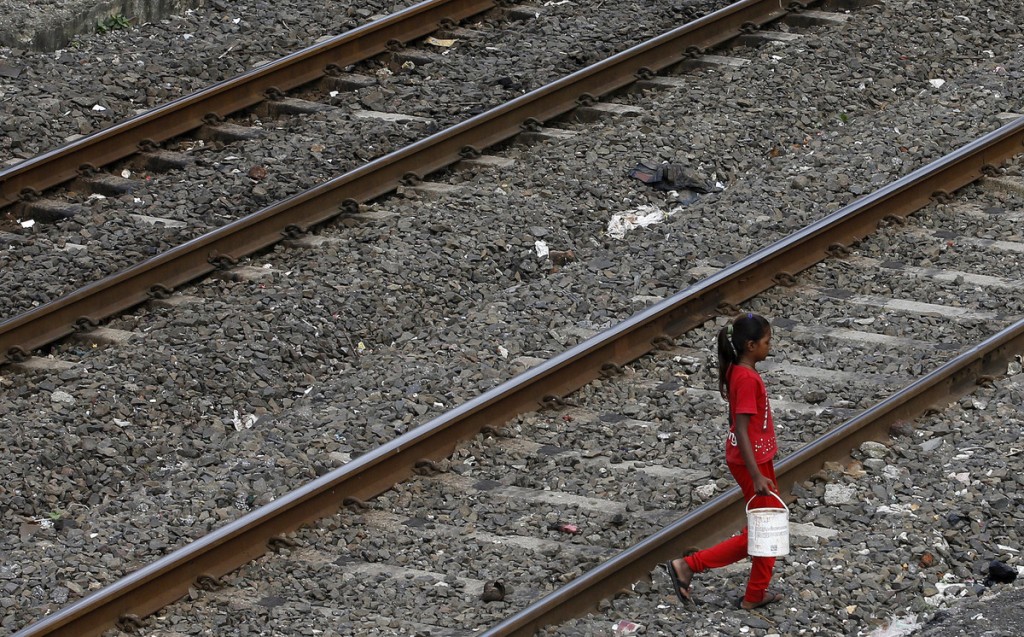 Hér ferðast ung, indversk stúlka yfir járnbrautarteina með fötu fulla af vatni - sem ætluð er til þvotta eftir að hún hefur haft hægðir utandyra. 