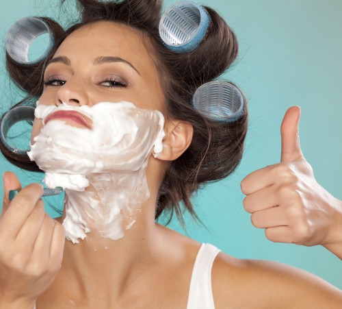 attractive young woman shaves her face and showing thumb up