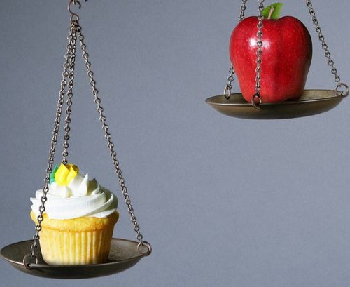 Scale weighing the value of a cupcake and apple