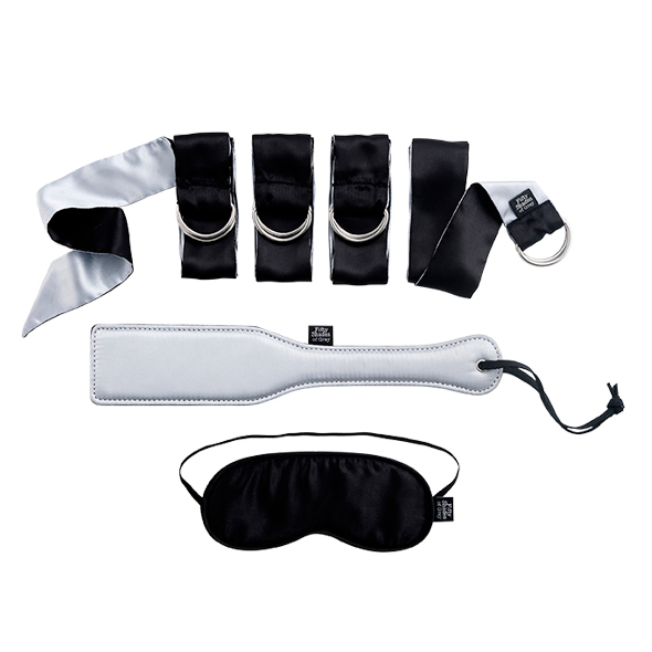 Finndu þína Christian Grey og Anastasiu Steele fantasíu með þessu frábæra fjötra setti fyrir byrjendur sem er tileinkað metsölu bókaseríunni 50 Shades of Grey. "Pleasure, pain, reward and punishment - his words from so long ago echo through my mind. His intention is clear. My inner goddess wakes, wide-eyed and raring to go. My skin tingles, my blood is racing, and there's nothing more I desire." - Anastasia Steele Settið samanstendur af mjúkum svörtum og silfurtlituðum satín böndum, satín augngrímu, flengispjaldi og satín poka til að geymslu.